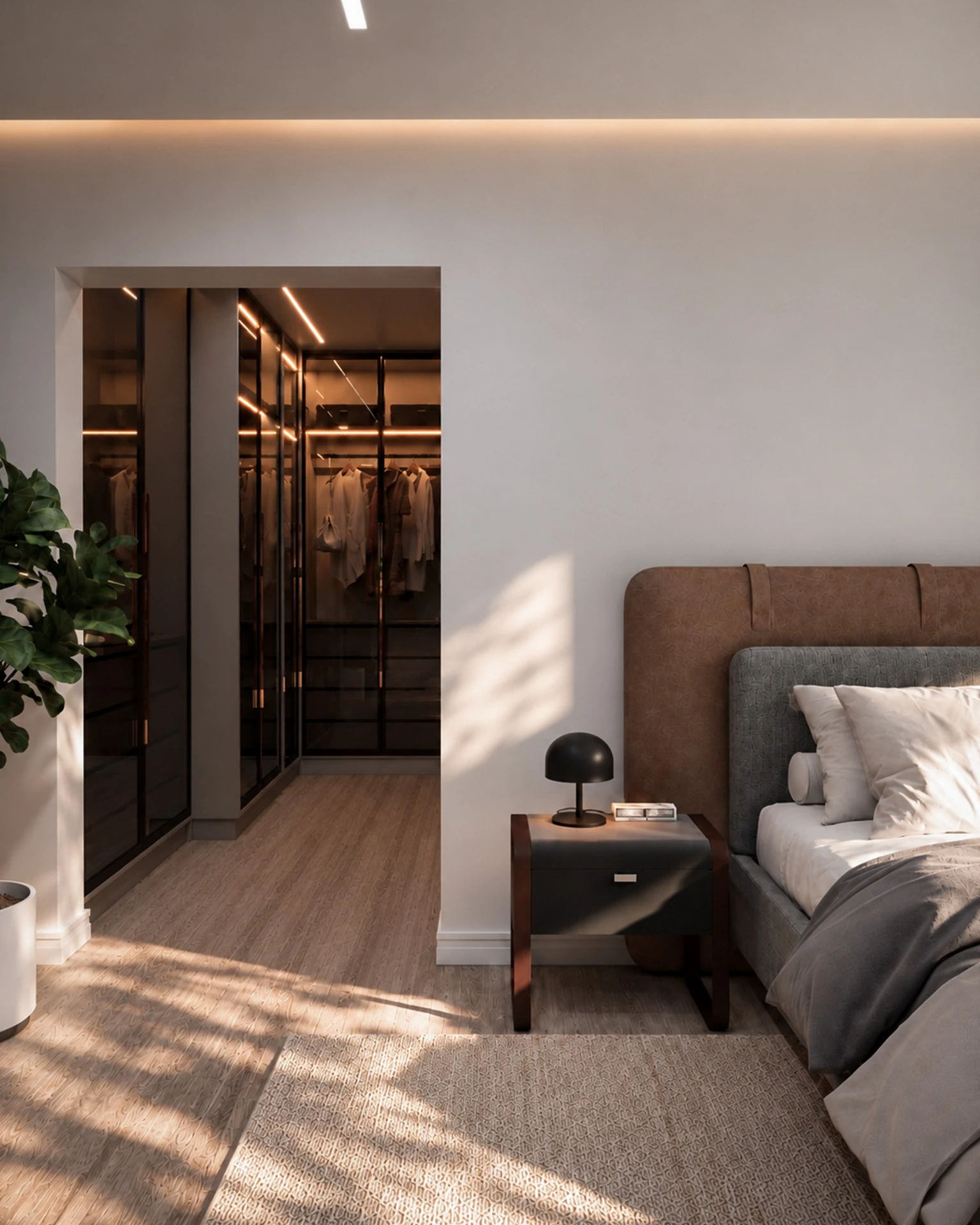 Vista da passagem entre dormitório e closet da Suíte Refúgio, com armários em madeira escura, iluminação embutida e parte da cama estofada em primeiro plano.